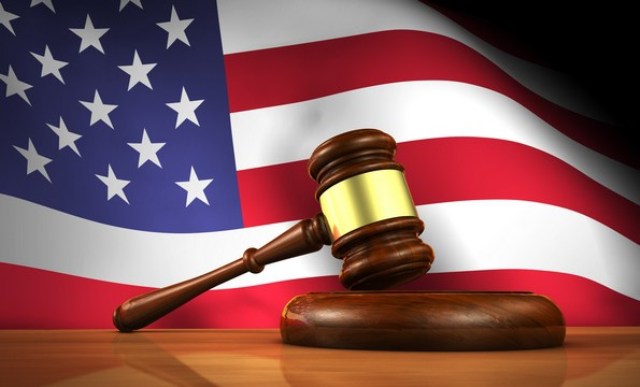 American law and justice concept with a 3d rendering of a gavel on a wooden desktop and the United States Of America flag on background.