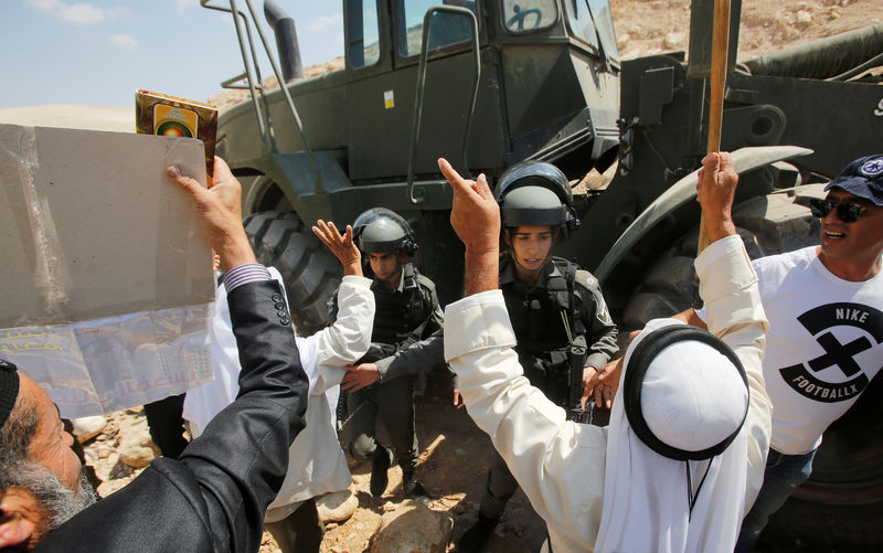 محتجون فلسطينيون وأجانب يتصدون لجرافة إسرائيلية قرب قرية الخان الأحمر بالضفة الغربية المحتلة يوم الجمعة. تصوير: موسى قواسمة - رويترز