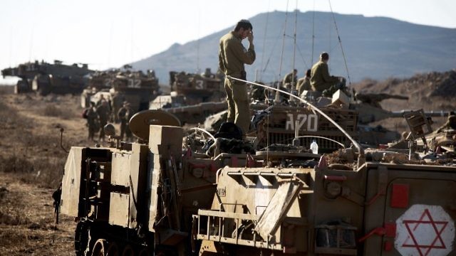 Israeli soldiers stand on an Armoured Personnel Carrier (APC) and on Merkava tanks in a training area in the Israeli-annexed Golan Heights during a brigade Armoured Corps Exercise on October 16, 2013. The Golan, seized by Israel from its Arab neighbour in the 1967 Six-Day War, has been mostly quiet since the 1973 Yom Kippur War. Tension, however, has risen since the 2011 start of the conflict in Syria between rebels and regime forces. AFP PHOTO/MENAHEM KAHANA