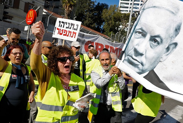 Israelis wearing yellow vests, carry banners and a picture of their Prime Minister Benjamin Netanyahu as they demonstrate against the rising cost of living on December 14, 2018, in the Israeli coastal city of Tel Aviv. Responding to a call on the social media, hundreds of demonstrators wearing yellow vests imitating the ongoing riots in France, protested today in Tel Aviv and Jerusalem against the announced increase of prices of goods and necessities and higher taxes. / AFP / JACK GUEZ