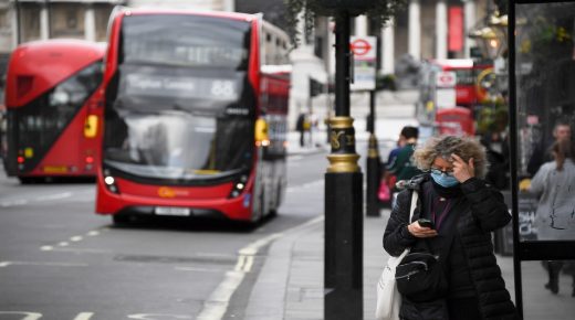 A woman wears a mask as a bus passes on March 17, 2020 in London, England. Boris Johnson held the first of his public daily briefings on the Coronavirus outbreak yesterday and told the public to avoid theatres and pubs and to work from home where possible. The number of people infected with COVID-19 in the UK has passed 1500 with 55 deaths. (Photo by Alberto Pezzali/NurPhoto via Getty Images)