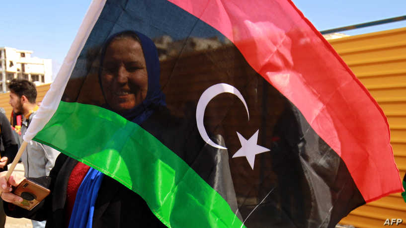 A woman waves a national flag as Libyans mark the 10th anniversary of the 2011 revolution, in the eastern city of Benghazi, on February 17, 2021. - The uprising toppled longtime ruler Moamer Kadhafi, ending a long-lived dictatorship but throwing the country into a decade of violent lawlessness. (Photo by Abdullah DOMA / AFP)