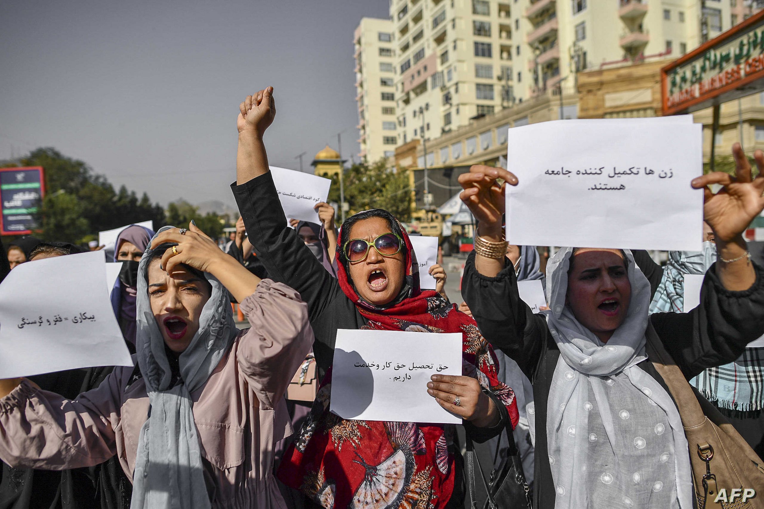 Afghan women chant slogans and hold placard during a women's rights protest in Kabul on October 21, 2021. - The Taliban violently cracked down on media coverage of a women's rights protest in Kabul on October 21 morning, beating several journalists. (Photo by BULENT KILIC / AFP)