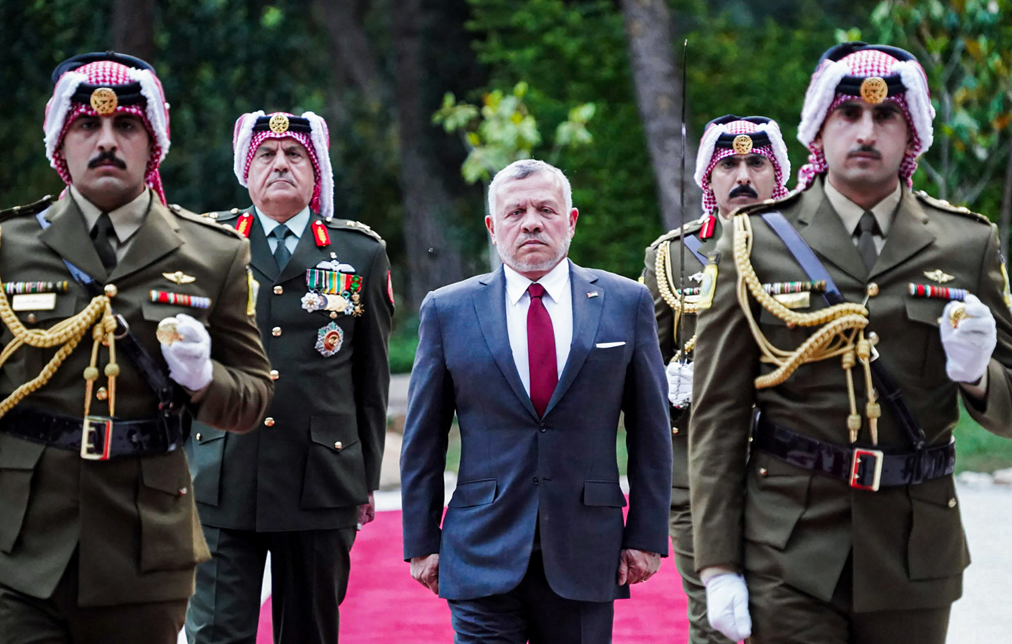 A handout picture released by the Jordanian Royal Palace on May 25, 2020 shows Jordanian King Abdullah II (C) walking with an honour guard during the official welcoming ceremony at the Royal Hashemite Court in the capital Amman, on the occasion of Jordan's 74th Independence Day. (Photo by Yousef ALLAN / Jordanian Royal Palace / AFP) / RESTRICTED TO EDITORIAL USE - MANDATORY CREDIT "AFP PHOTO / JORDANIAN ROYAL PALACE / YOUSEF ALLAN" - NO MARKETING NO ADVERTISING CAMPAIGNS - DISTRIBUTED AS A SERVICE TO CLIENTS